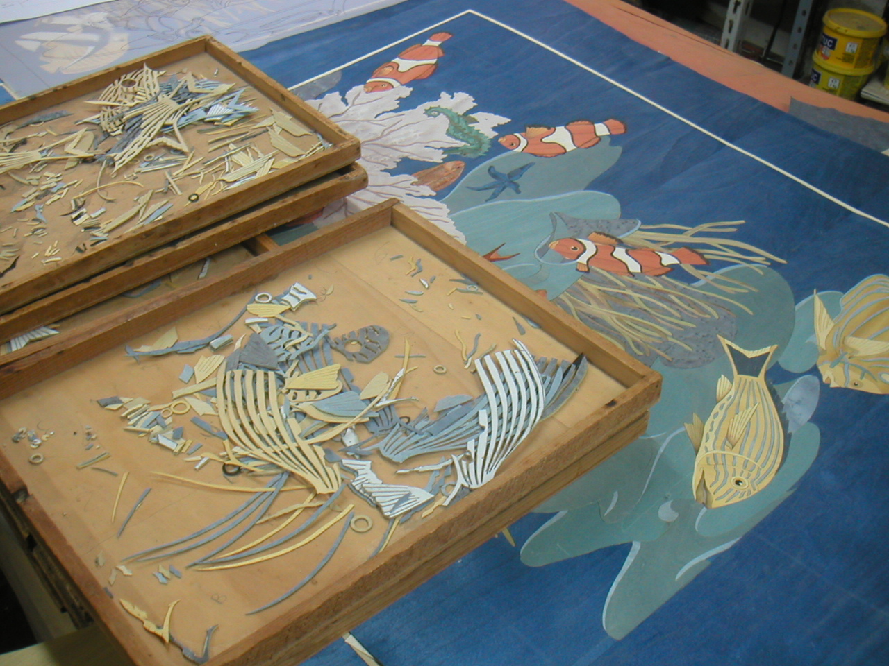 Hands assembling a Sorrento landscape marquetry panel — trees and mountains in natural veneer tones