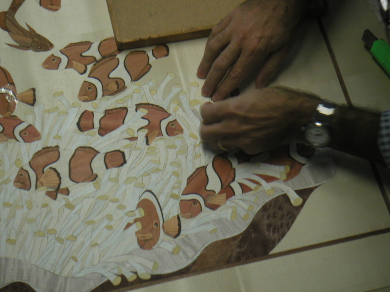Hands guiding stacked veneers through the cutting blade